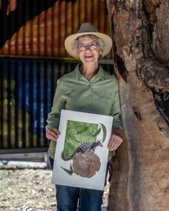 Southern Highlands artist Gillian Baldock holding wildlife artwork featuring a numbat in Bowral