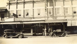 Historic photograph of Springett's Dining Rooms in Bowral, NSW, showing the original shopfront, vintage cars and pedestrians.